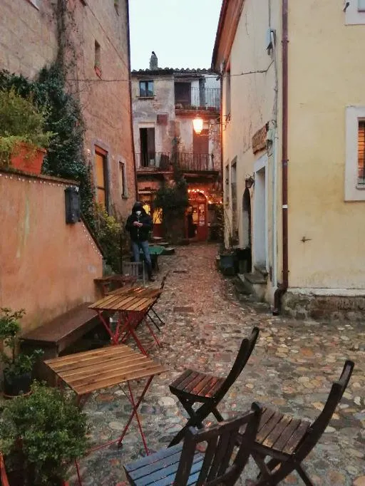 Vicolo stretto con tavolini e sedie in legno
