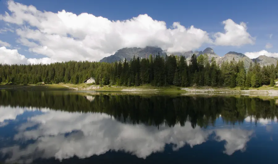 Lago alpino in Valmalenco con riflessi di montagne e nuvole