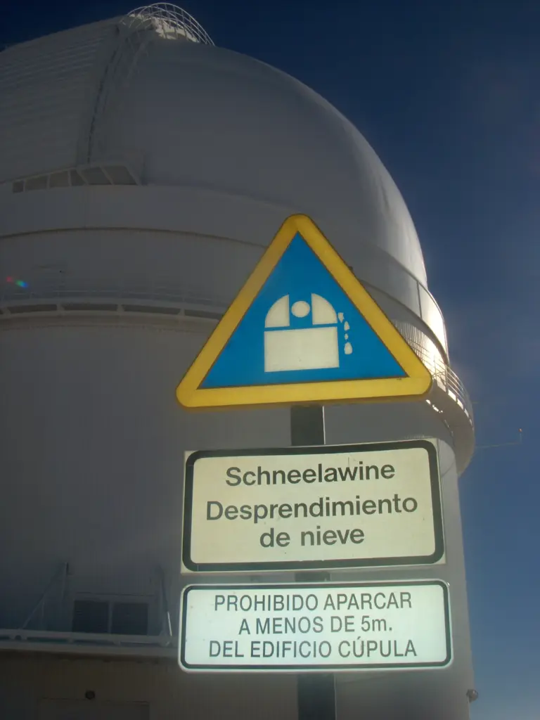 Cupola di un telescopio dell'Osservatorio di Calar Alto con cartelli di avviso caduta neve in tedesco e spagnolo