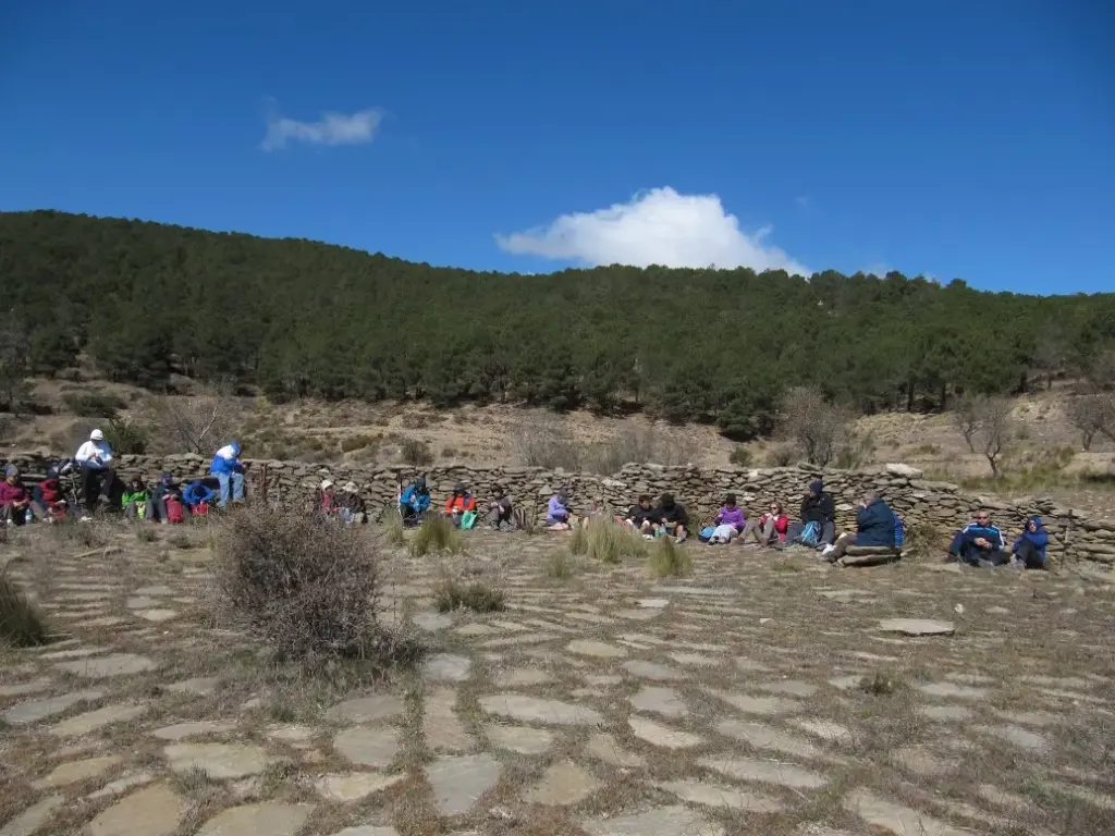 Gruppo di escursionisti in pausa presso un antico muretto a secco nella Sierra de los Filabres, con pineta sullo sfondo