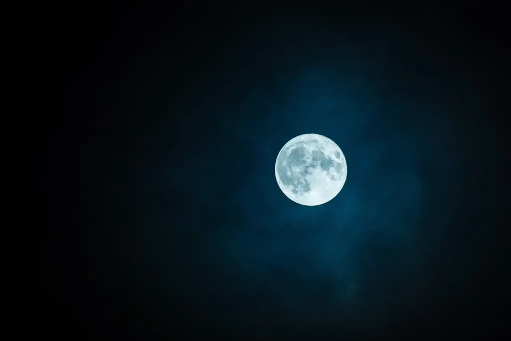 Luna piena nitida in un cielo notturno scuro, con un sottile alone bluastro