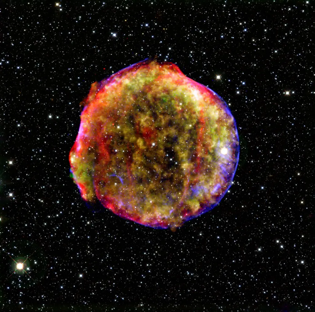 Immagine composita multi-lunghezza d'onda del residuo della supernova di Tycho, una struttura sferica dai colori rosso, oro e blu su sfondo stellato