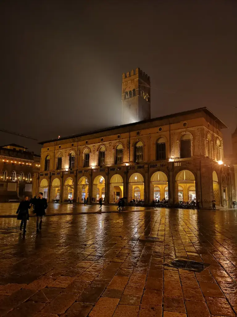 Piazza Maggiore a Bologna illuminata di notte sotto la pioggia
